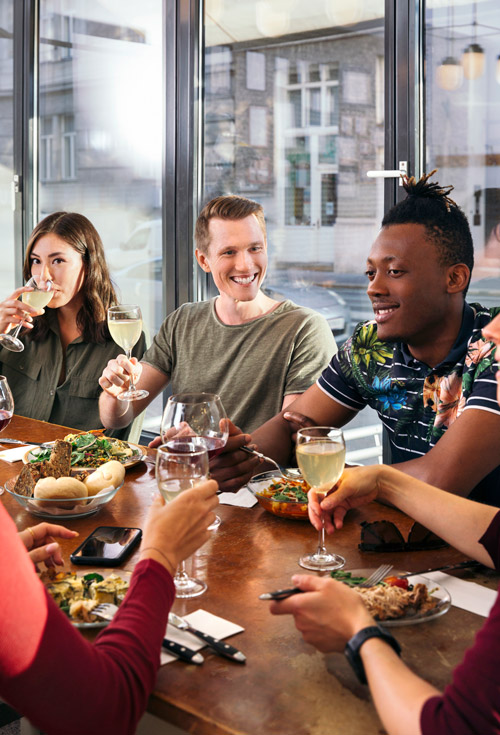 Friends sharing plates of food around a busy restaurant table
